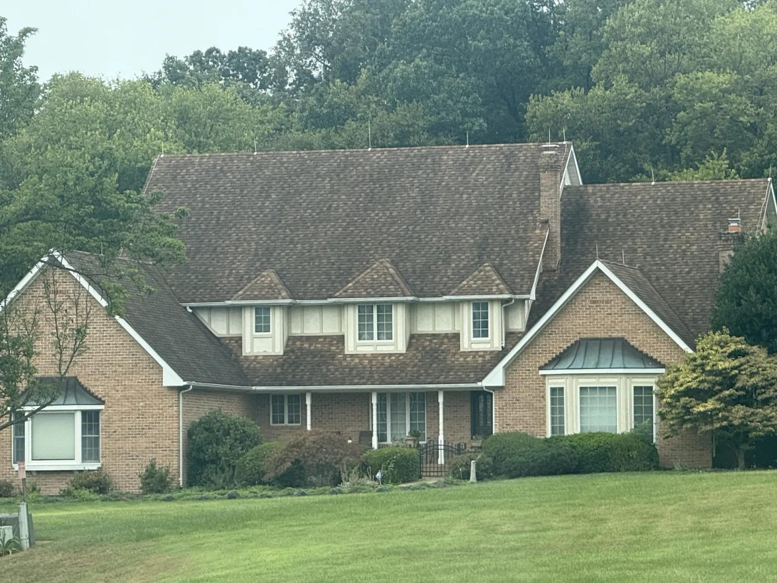 Brick home with an aging shingle roof before rejuvenation in Winchester VA